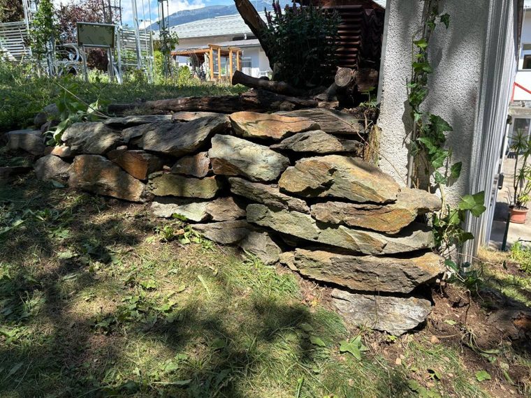 Aus flachen Natursteinen aufgeschichtete Trockensteinmauer am Rand des Lehrpfadgeländes